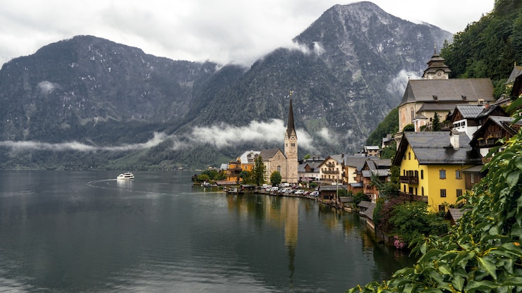 Foto gratuito paisaje de hallstatt rodeado de agua y montañas rocosas durante un día lluvioso en austria