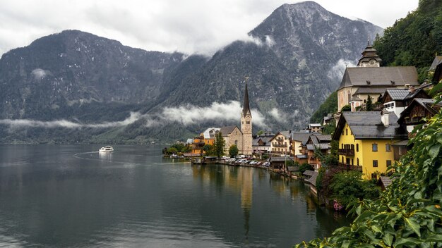 Paisaje de Hallstatt rodeado de agua y montañas rocosas durante un día lluvioso en Austria