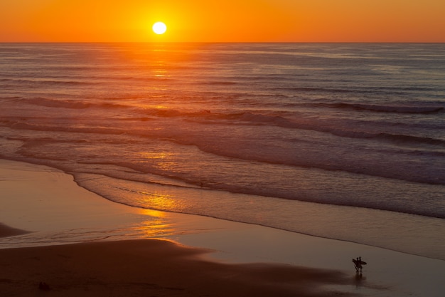 Paisaje de una hermosa puesta de sol que se refleja en el mar desde la playa en Portugal, Algarve