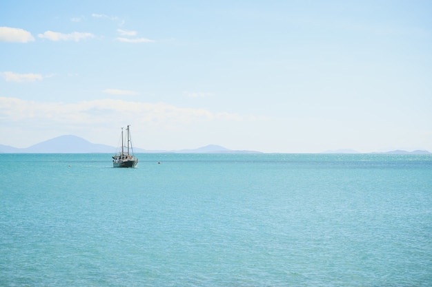 Paisaje del mar con un barco bajo un cielo azul y la luz del sol