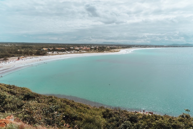 Paisaje del mar rodeado por una isla cubierta de vegetación bajo un cielo nublado