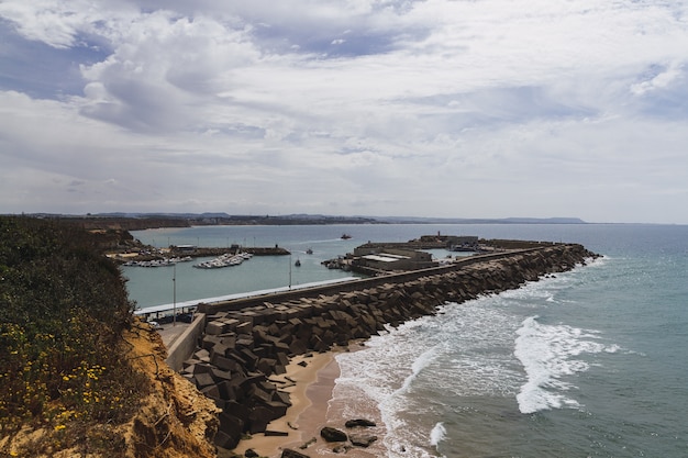 Paisaje del mar rodeado de rocas bajo un cielo nublado y la luz del sol durante el día