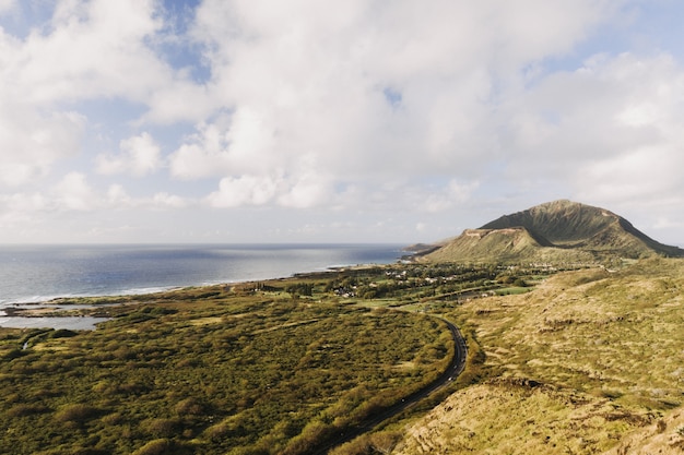 Paisaje del mar rodeado de vegetación bajo un cielo nublado y la luz del sol