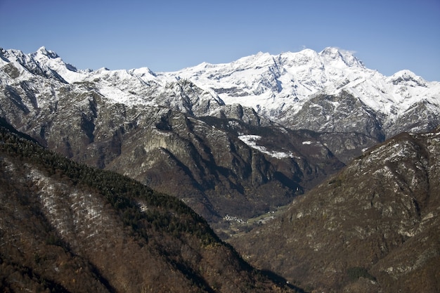 Paisaje de montañas cubiertas de árboles y nieve bajo la luz del sol y un cielo azul