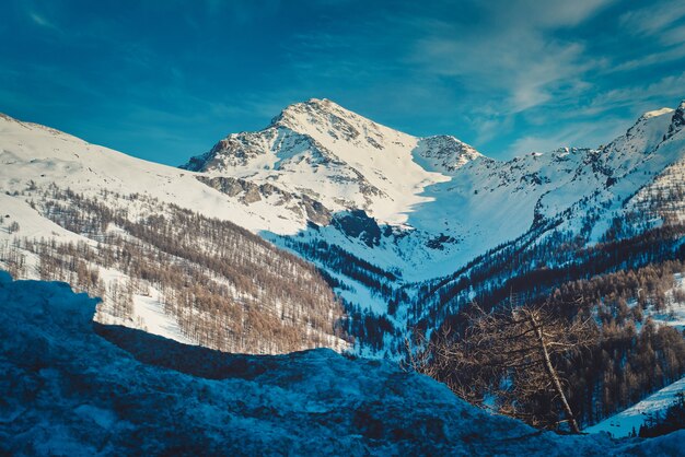 Paisaje de montañas rocosas cubiertas de nieve bajo la luz del sol en Sestriere en Italia