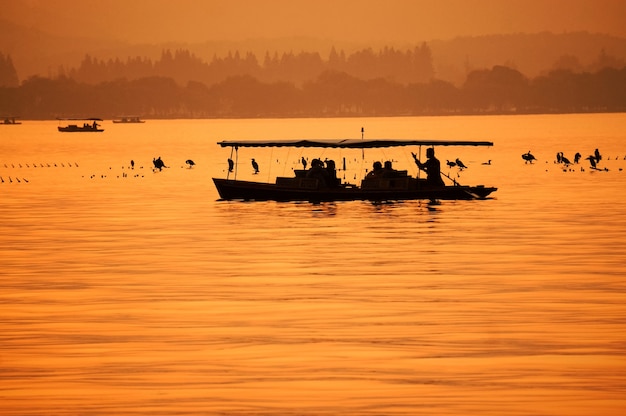 Paisaje naranja con pescador en su barco