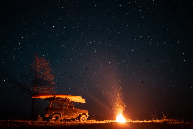 Foto gratuita paisaje nocturno con fogata brillante y coche