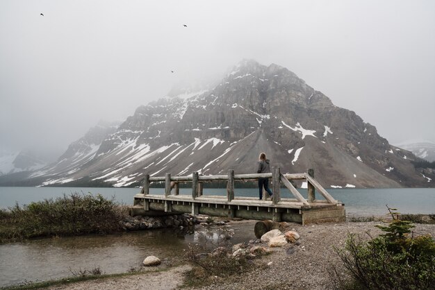 Paisaje de una persona de pie en un muelle que conduce al río en la formación rocosa