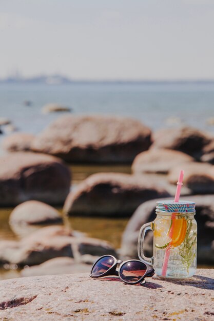 Paisaje de playa con gafas de sol y bebida refrescante 