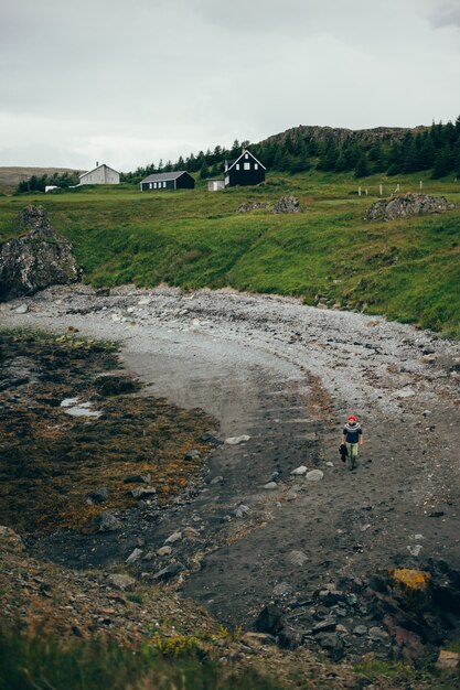 Paisaje de playa islandesa, el hombre camina en suéter