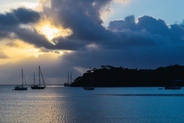 Paisaje de puesta de sol con una silueta de montaña y barcos en el mar