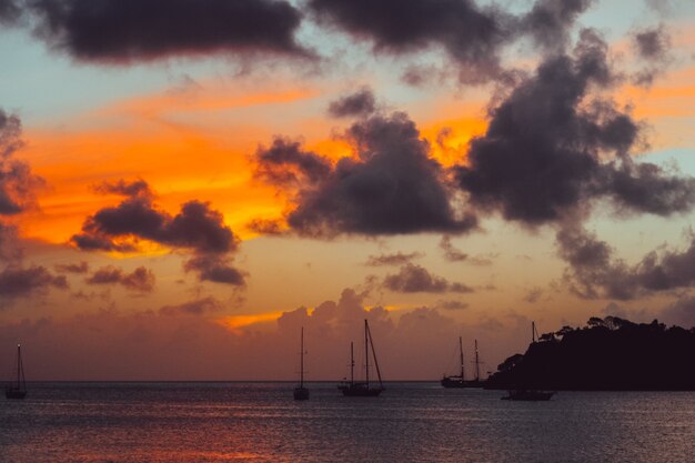 Paisaje de puesta de sol con una silueta de montaña y barcos en el mar