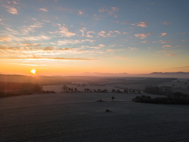 Paisaje de puesta de sol con vistas a los árboles en el campo y las montañas