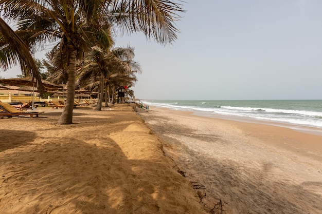 Paisaje de un resort de playa rodeado de palmeras y el mar bajo un cielo azul en Gambia