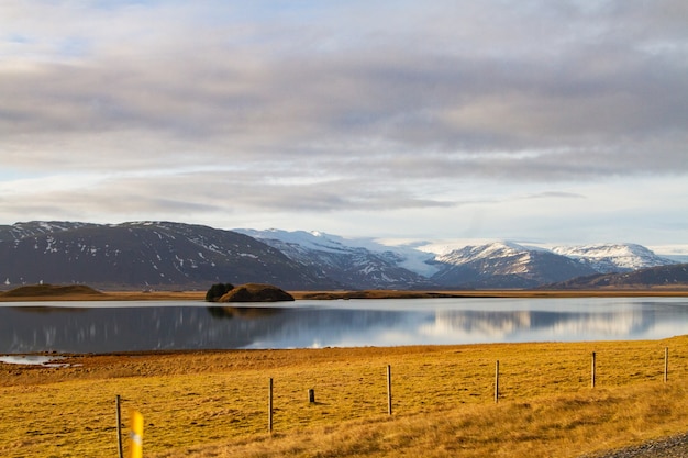 Foto gratuita paisaje de un río rodeado de colinas cubiertas de nieve y reflejándose en el agua en islandia