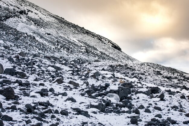 Paisaje rocoso de las montañas nevadas bajo un cielo nublado durante el día