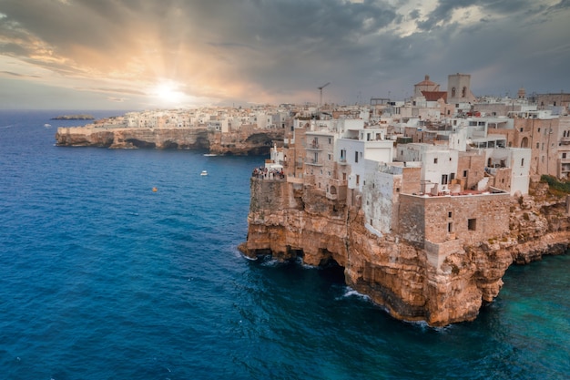 Paisaje urbano de Polignano a Mare rodeado por el mar bajo la luz del sol y un cielo nublado en Italia