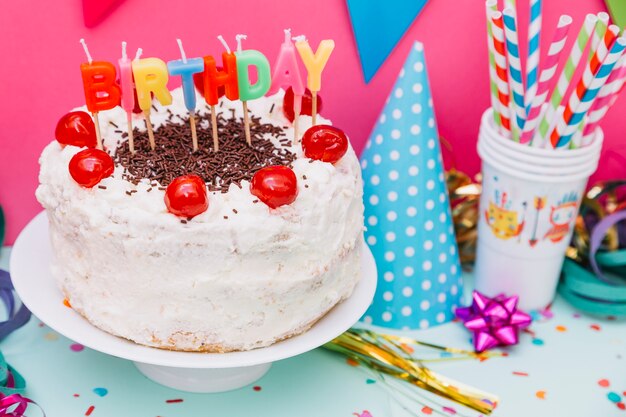 Pajitas de beber; Sombrero de fiesta y pastel de cumpleaños en soporte de pastel