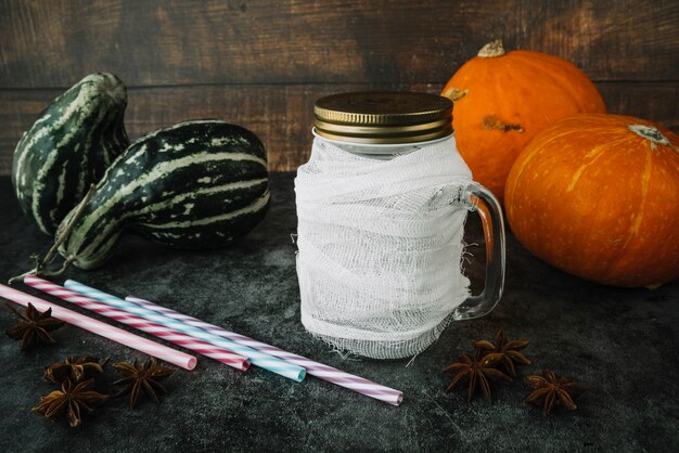 Pajitas y bebidas cerca de especias y calabazas