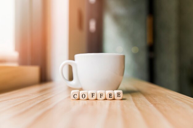 Palabra de café con una taza de café en la superficie de madera
