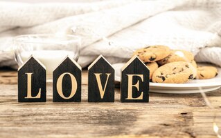 Foto gratuita palabra decorativa amor en un fondo borroso con un vaso de leche y galletas