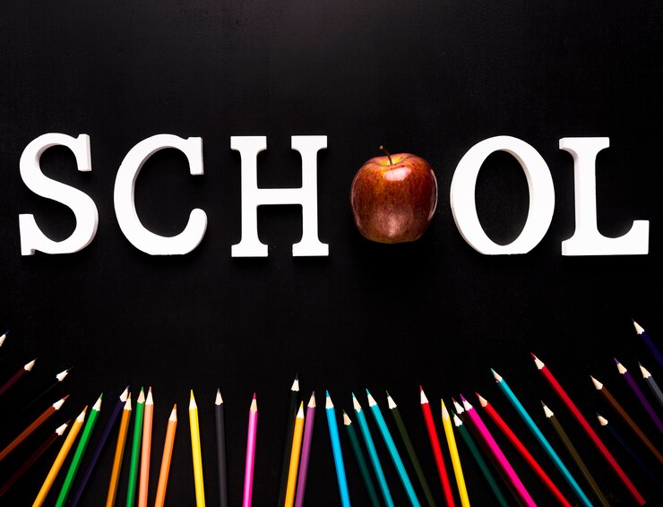 Foto gratuito palabra de la escuela y lápices de colores esparcidos sobre fondo negro