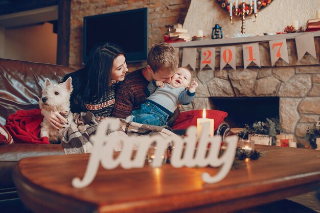 Palabra "family" con una familia sentada en el sofá de fondo en navidad