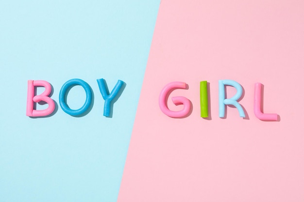 La palabra niño niña está hecha de plasticina de color sobre un fondo rosado azul