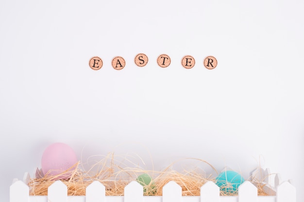 Palabra de Pascua cerca de huevos brillantes entre heno en caja