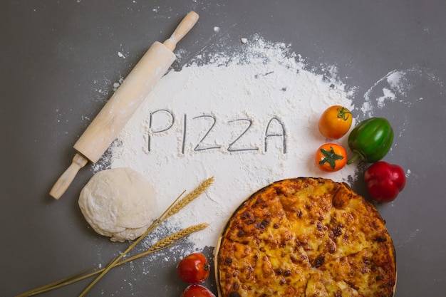 Palabra pizza escrita en harina con una sabrosa pizza