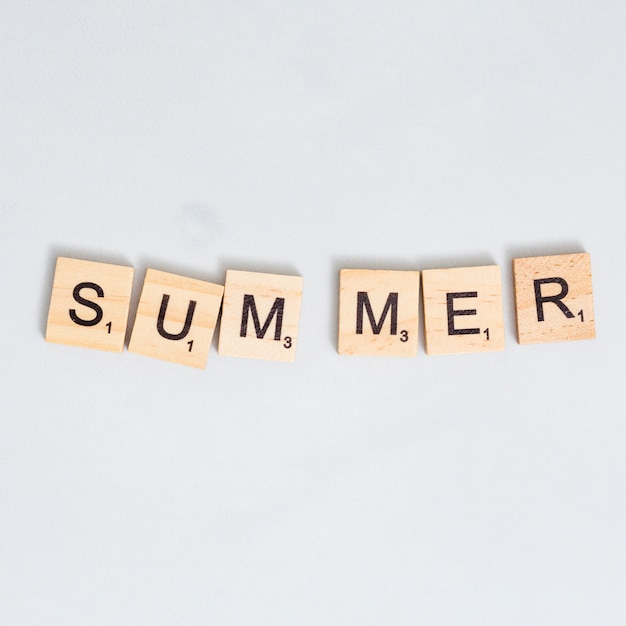 Palabra de verano escrita en bloque de madera sobre superficie gris
