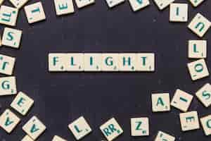 Foto gratuita palabra de vuelo dispuesta sobre fondo negro rodeado de letras scrabble