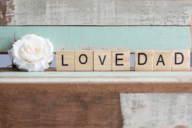 Foto gratuita palabras del papá del amor con la rosa blanca en la tabla rústica del vintage