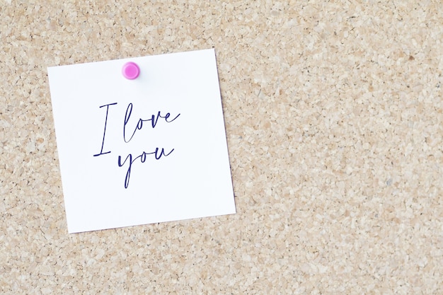 Palabras "Te amo" en un papel pegado a una pizarra con un alfiler