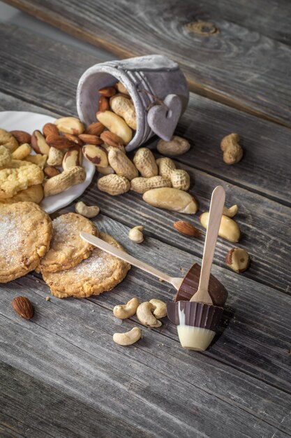 Paleta de chocolate en forma de una taza pequeña y varias nueces en un cubo de madera