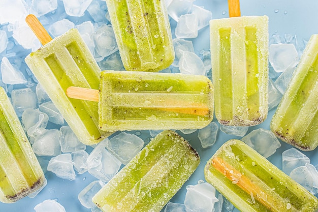 Foto gratuita paleta de helado de kiwi sobre fondo de tablero de madera