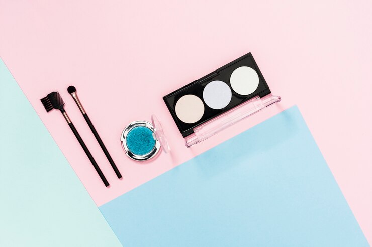 Foto gratuito paleta de sombra de ojos con pincel de maquillaje sobre fondo de color