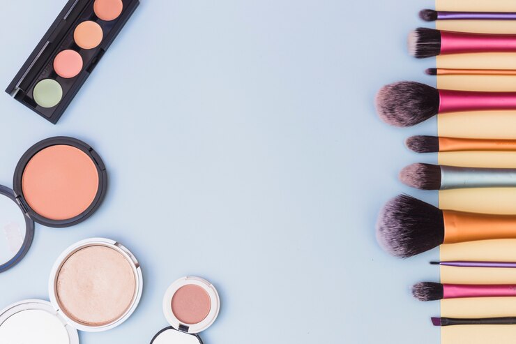 Foto gratuito paleta de sombras de ojos; colorete y pinceles de maquillaje sobre fondo azul