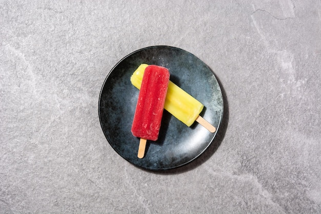 Paletas de fresa y limón sobre fondo de piedra gris