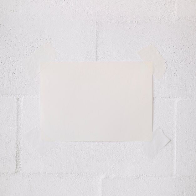 Palillo de papel en blanco blanco con cinta sobre fondo de pared blanca