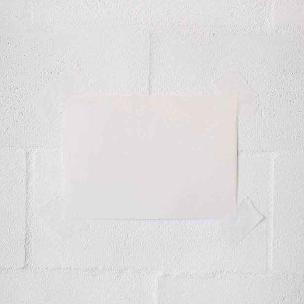 Palillo de papel en blanco blanco con cinta sobre fondo de pared blanca