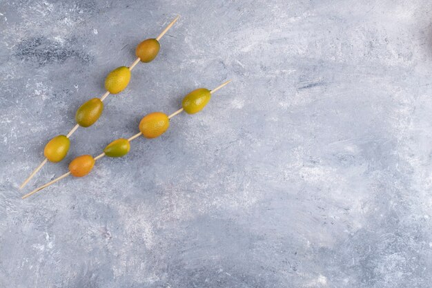 Palillos con kumquats frescos sobre un fondo de mármol.