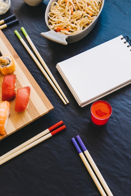 Palillos de primer plano cerca de sake y cuaderno