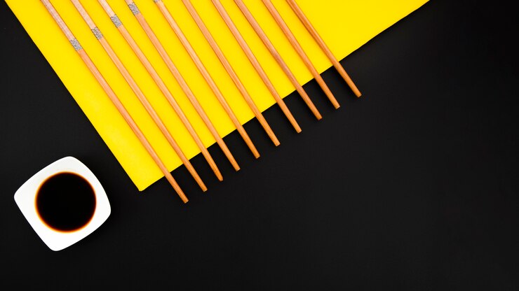 Foto gratuito palillos con tazón de salsa de soja sobre un fondo amarillo y negro