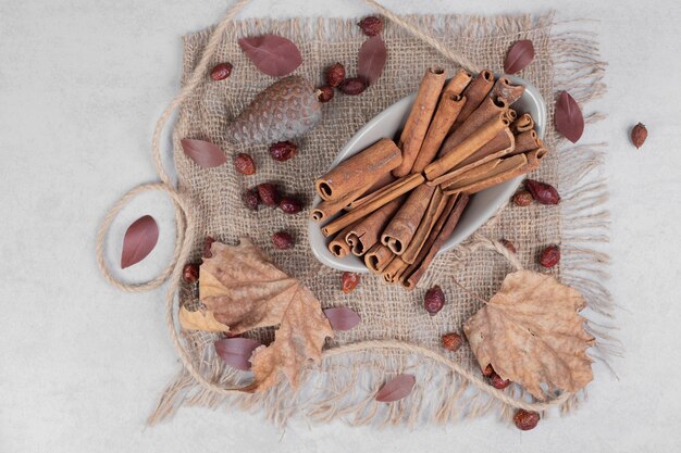 Palitos de canela, hojas y cuerda sobre arpillera. Foto de alta calidad