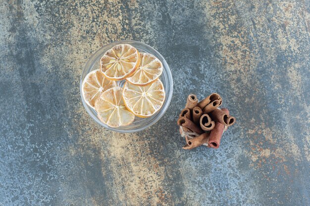 Palitos de canela y limones en rodajas sobre mármol.