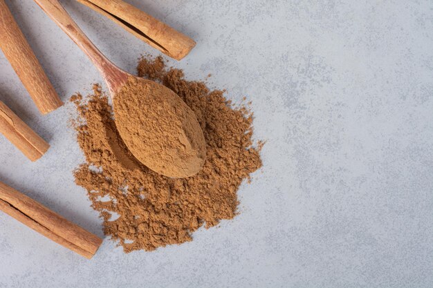 Palitos de canela y polvo mezclado en una cuchara de madera.