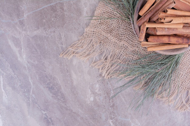 Palitos de canela en una taza de madera con rama de roble alrededor