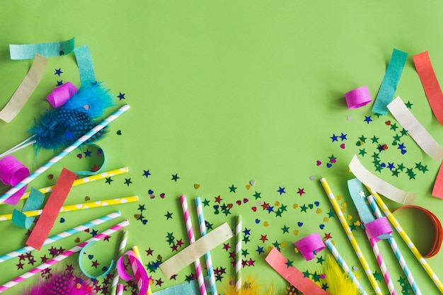 Palitos de colores con confeti debajo sobre una mesa verde