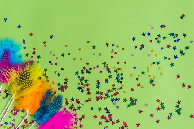 Palitos de colores con confeti debajo sobre una mesa verde